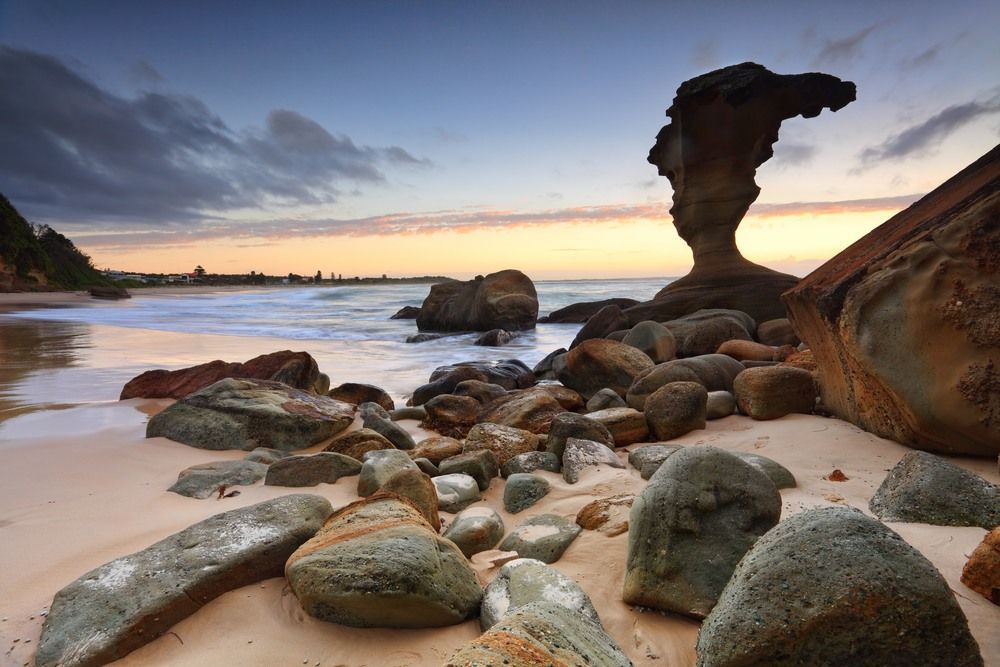 A Rock Formation On A Beach With A Sunset In The Background — InStyle Shower Screens & Wardrobes in Wyong, NSW