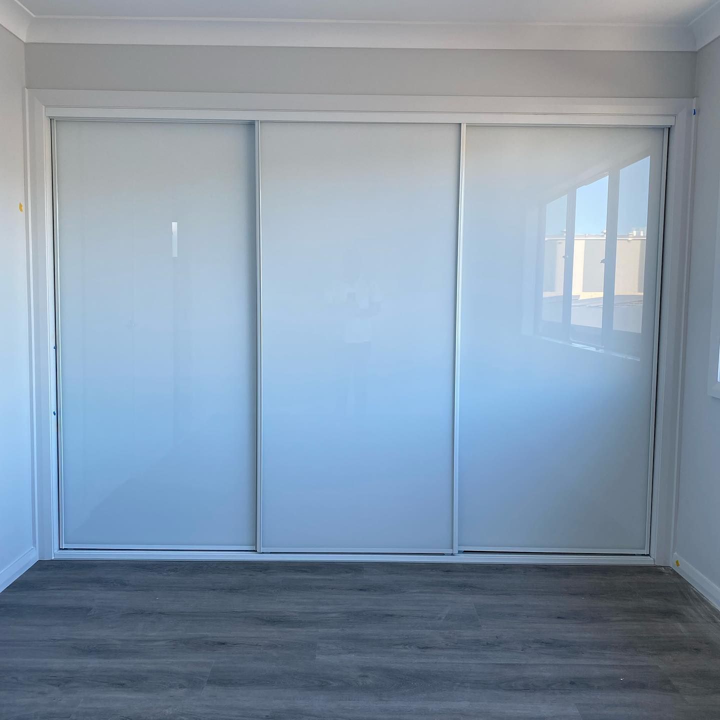An Empty Room With Sliding Glass Doors And A Wooden Floor — InStyle Shower Screens & Wardrobes in Charmhaven, NSW