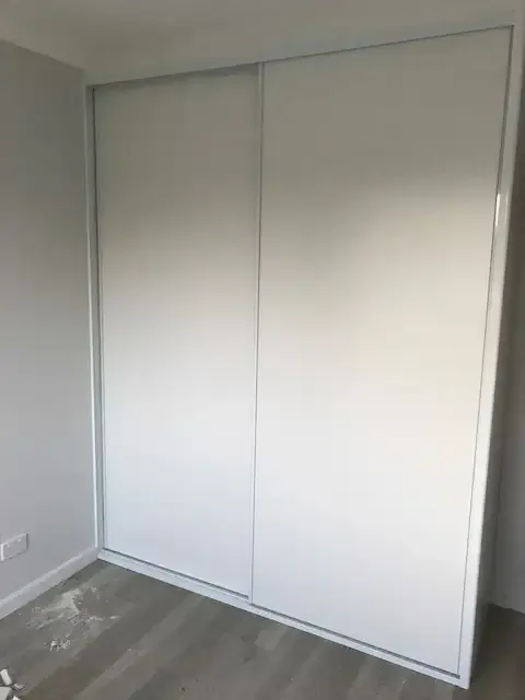 A White Wardrobe With Sliding Doors In A Room — InStyle Shower Screens & Wardrobes in Charmhaven, NSW