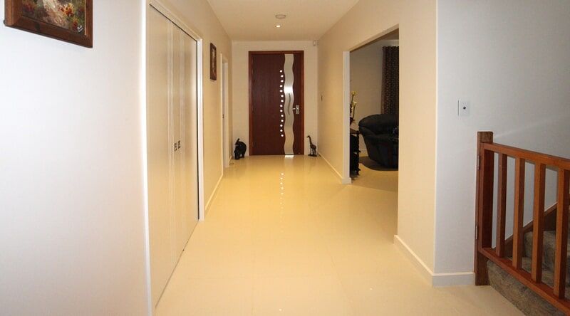 A Long Hallway with A Wooden Railing and A Brown Door — Leader Constructions in Cranbrook, QLD