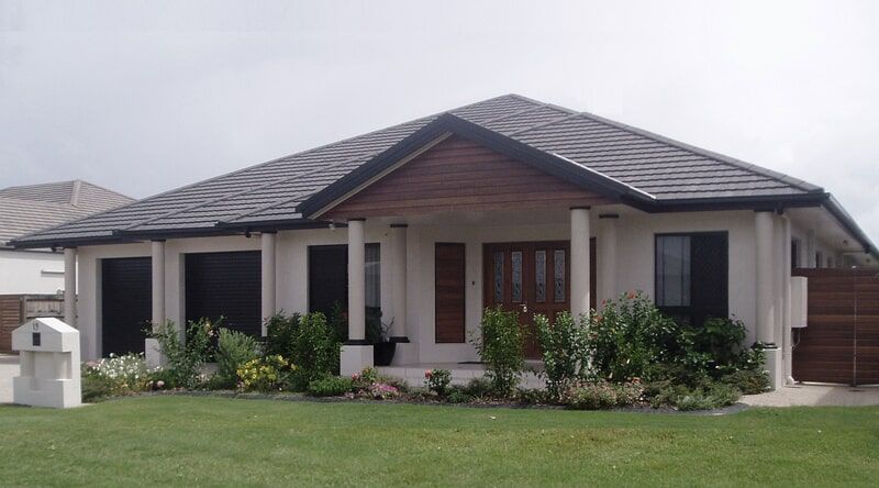 A White House with A Black Roof and Small Plants in Front of it — Leader Constructions in Cranbrook, QLD