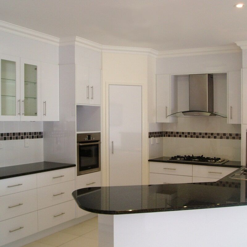 A Kitchen with White Cabinets and Black Counter Tops — Leader Constructions in Cranbrook, QLD