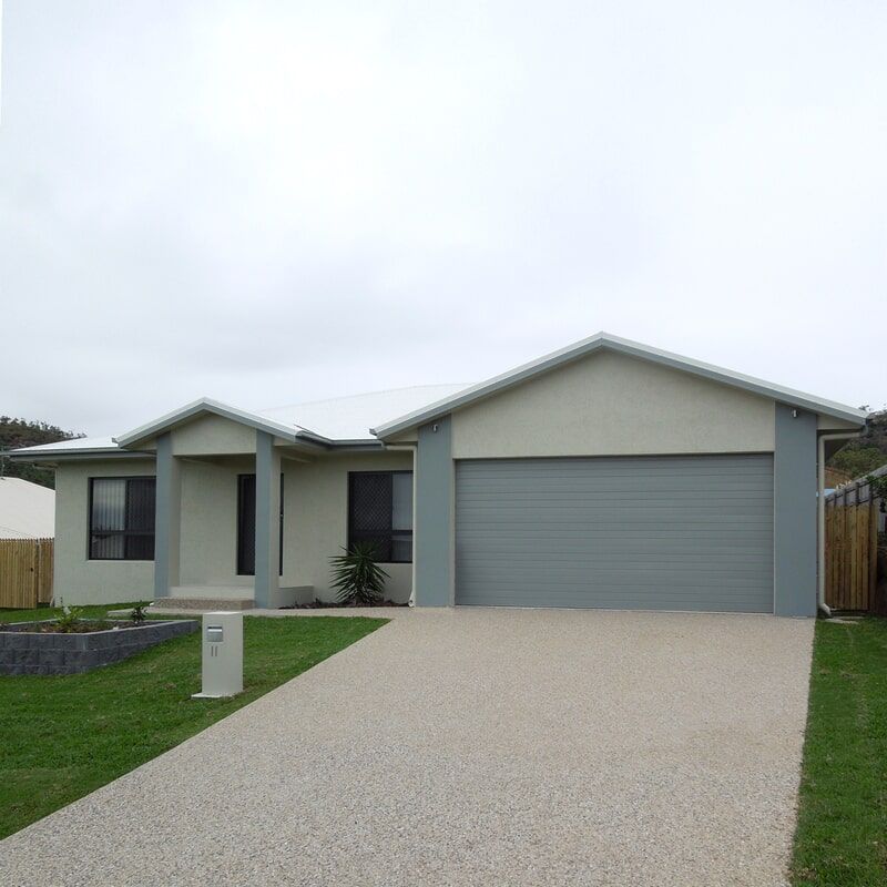 A House with A Gray Garage Door and A Gravel Driveway — Leader Constructions in Cranbrook, QLD