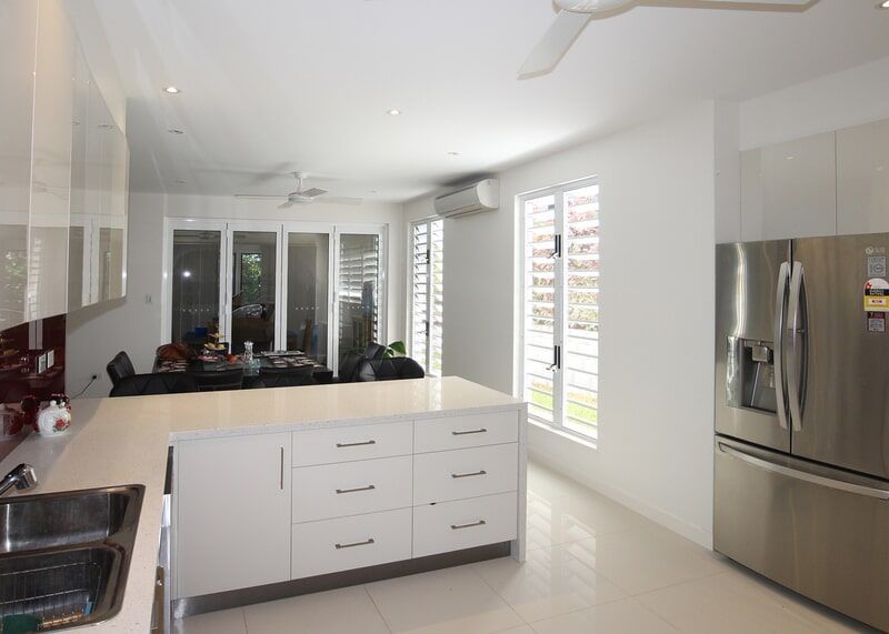 A Kitchen with A Stainless Steel Refrigerator, Sink, and Island — Leader Constructions in Cranbrook, QLD