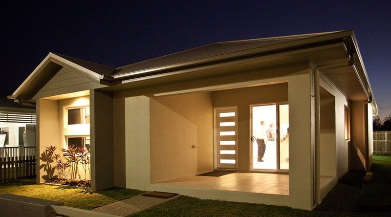 A House with A Sliding Glass Door Is Lit up At Night  — Leader Constructions in Cranbrook, QLD