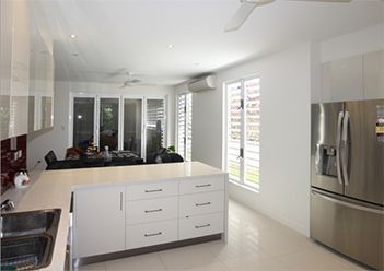 A Kitchen with White Cabinets, Stainless Steel Appliances, and A Large Island — Leader Constructions in Cranbrook, QLD