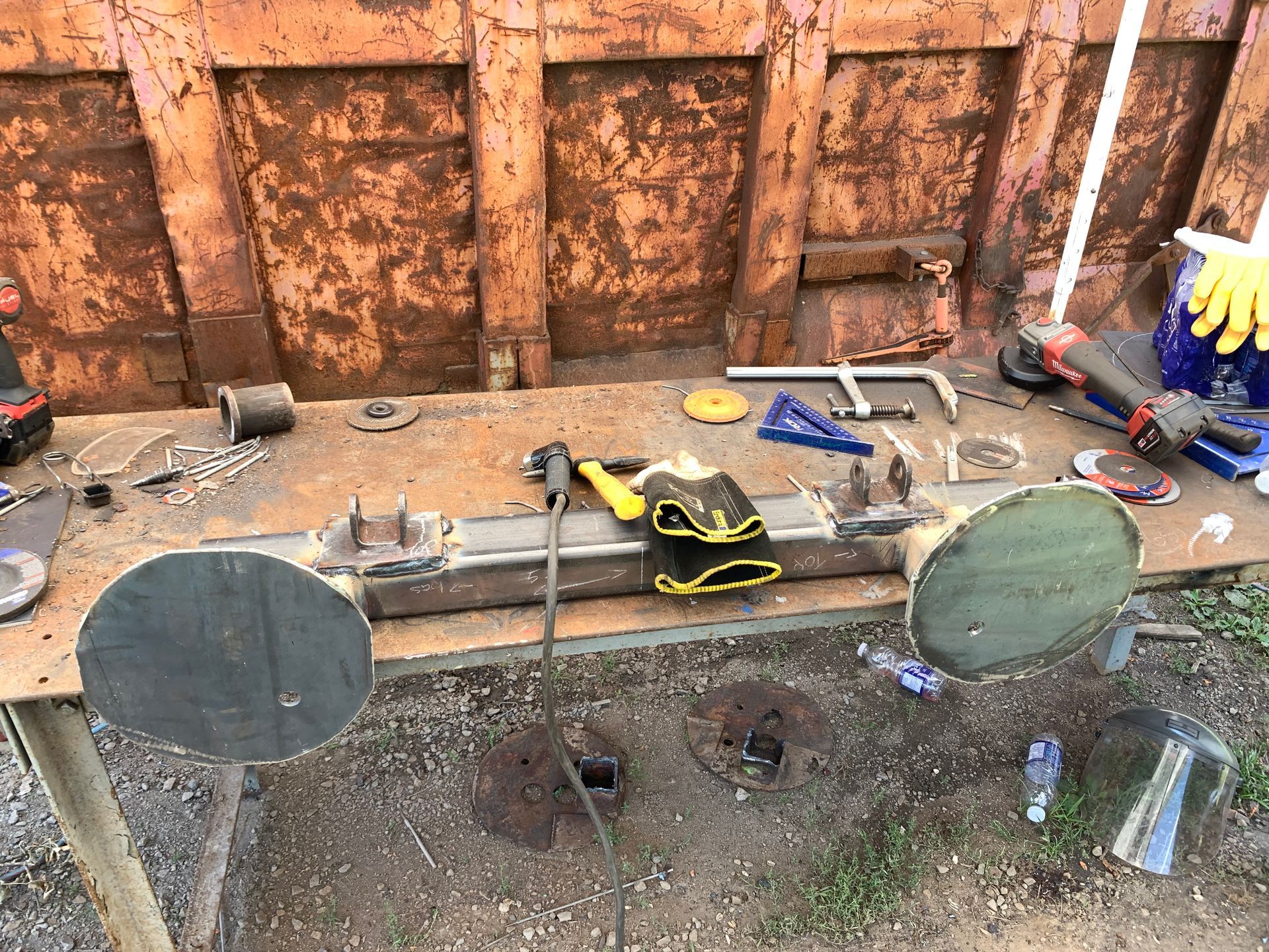 Travaux de fabrication métallique en cours sur un établi. Outils et pièces de soudage éparpillés sur une surface métallique.