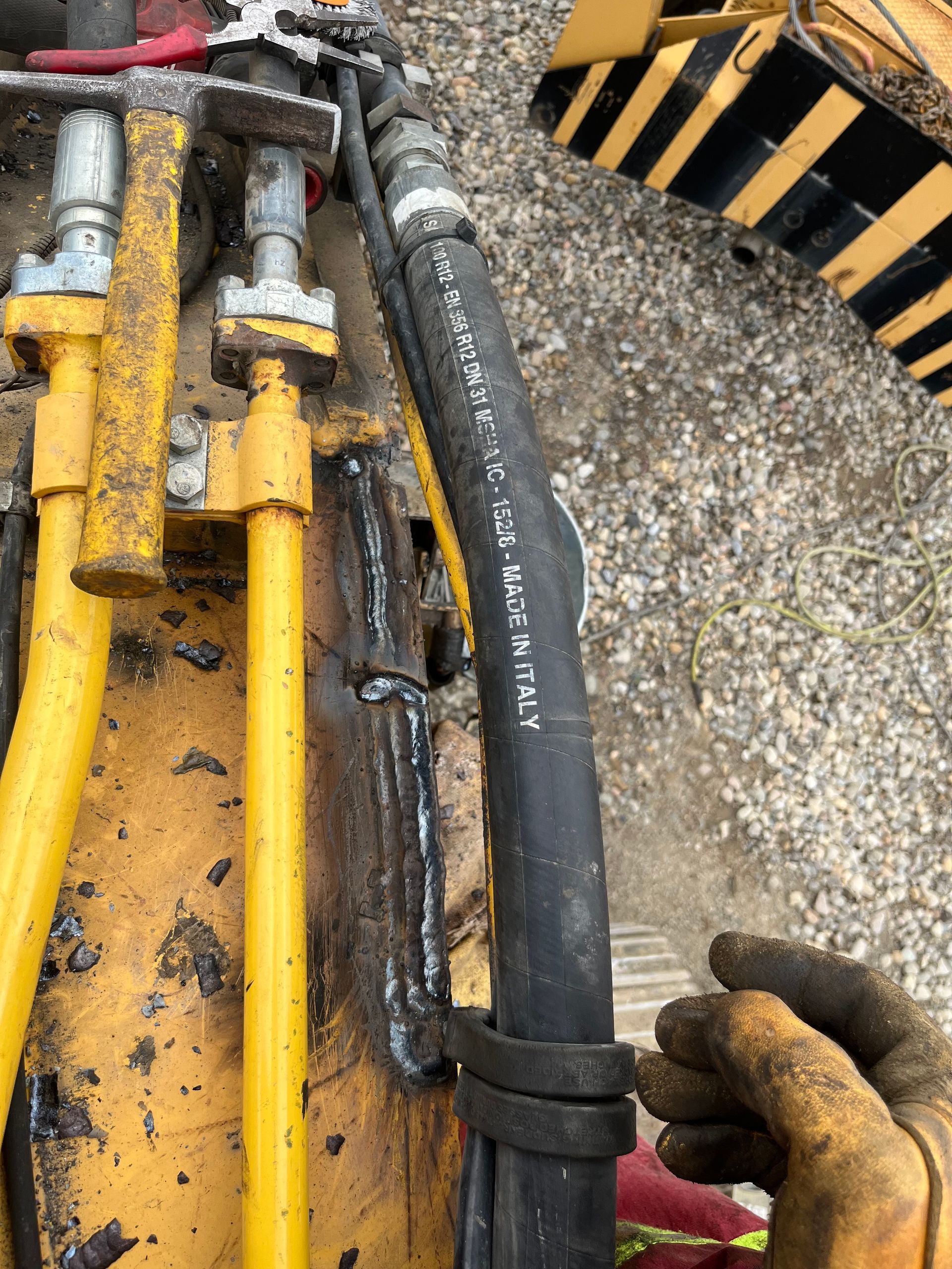 Gros plan sur des flexibles hydrauliques et des composants métalliques d'une machinerie lourde.