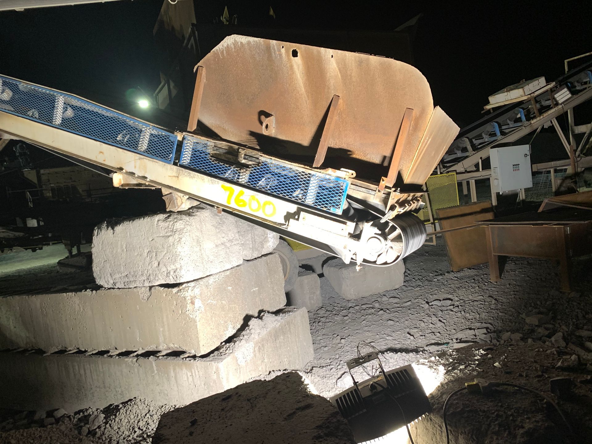 Système de convoyeur industriel au-dessus de blocs de béton dans un environnement faiblement éclairé.