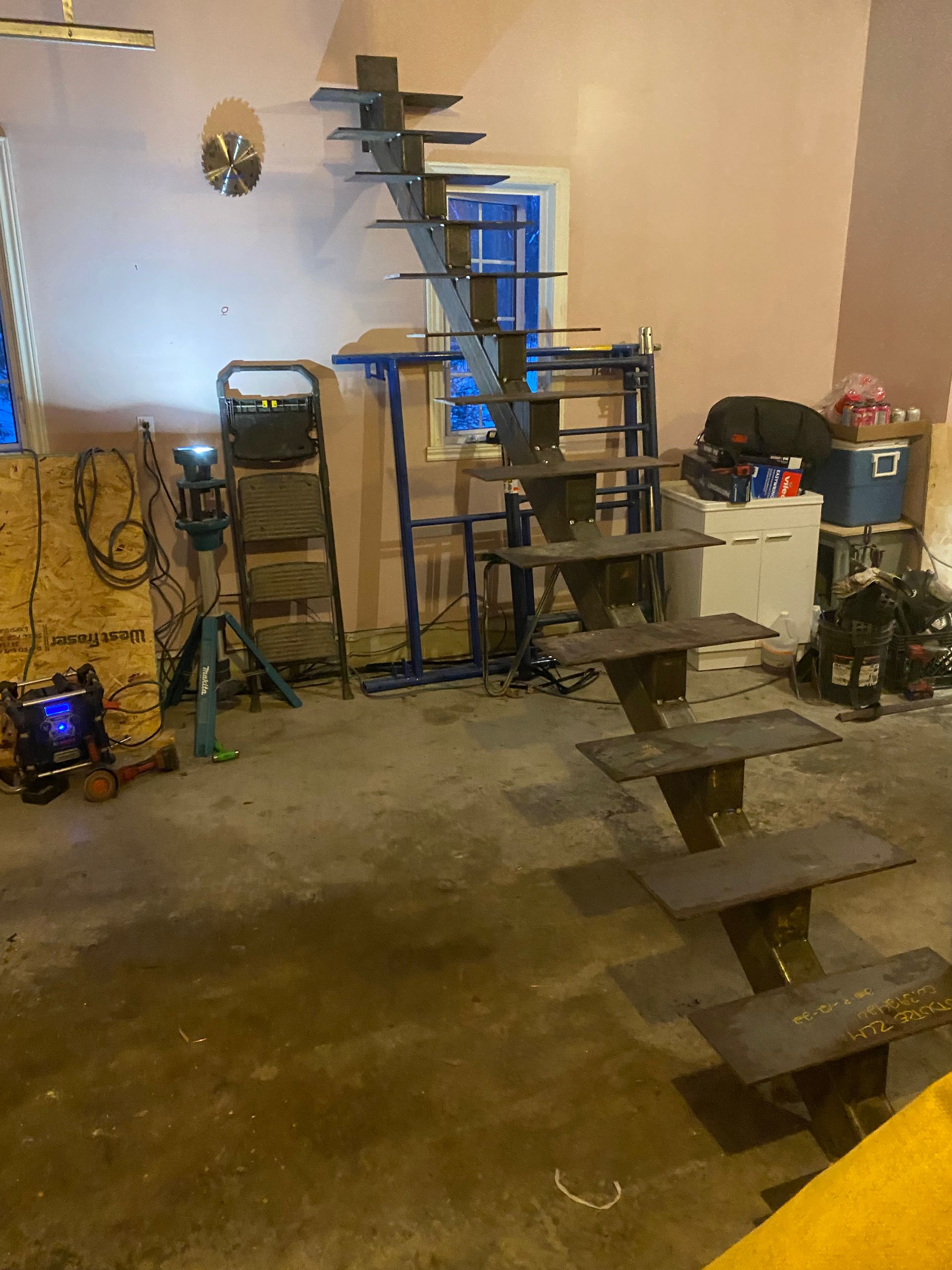 Escalier métallique en cours de fabrication dans un atelier ; les marches sont soudées à un support central.