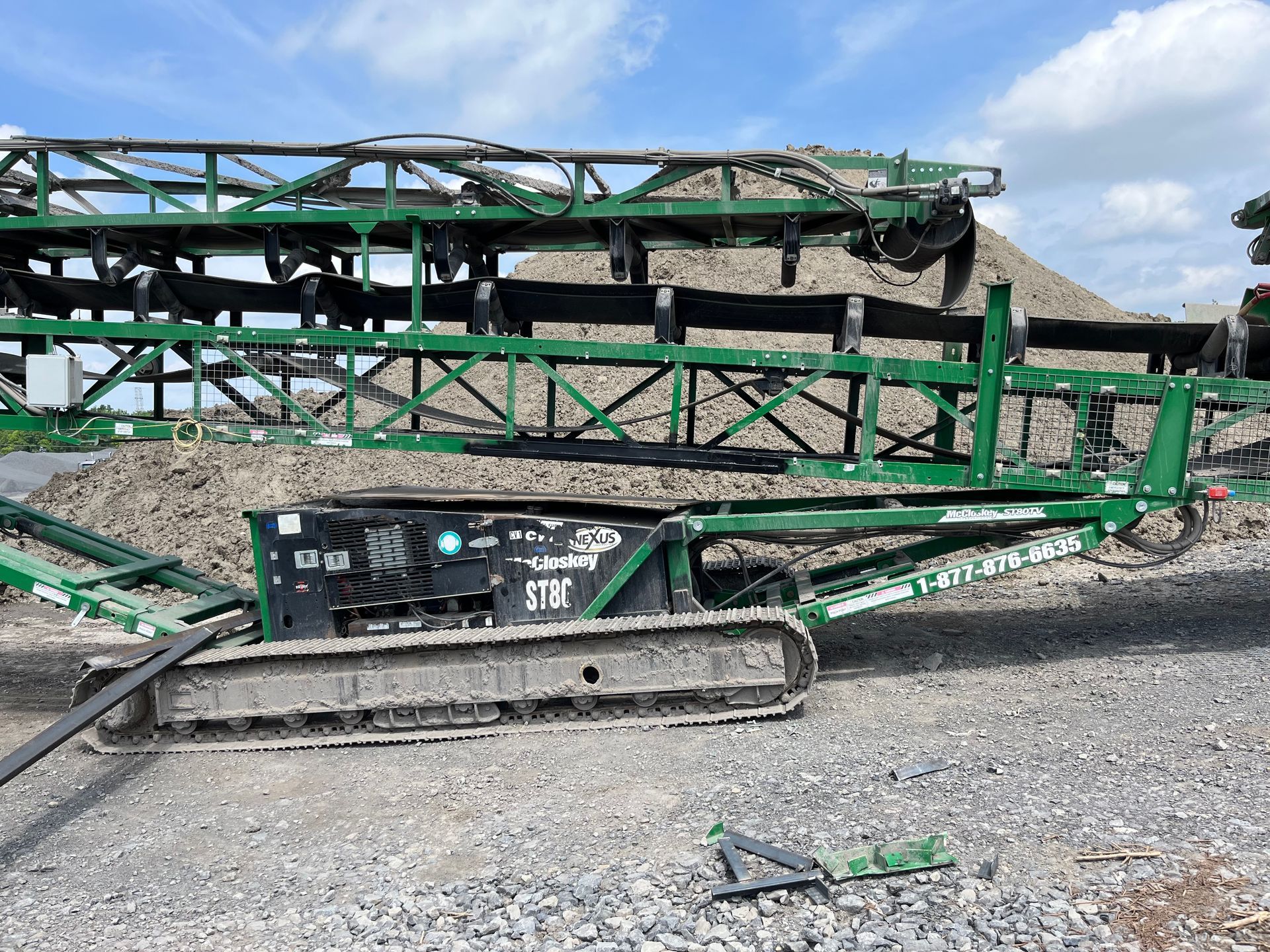 Convoyeur mobile chenillé vert triant du gravier dans une carrière.