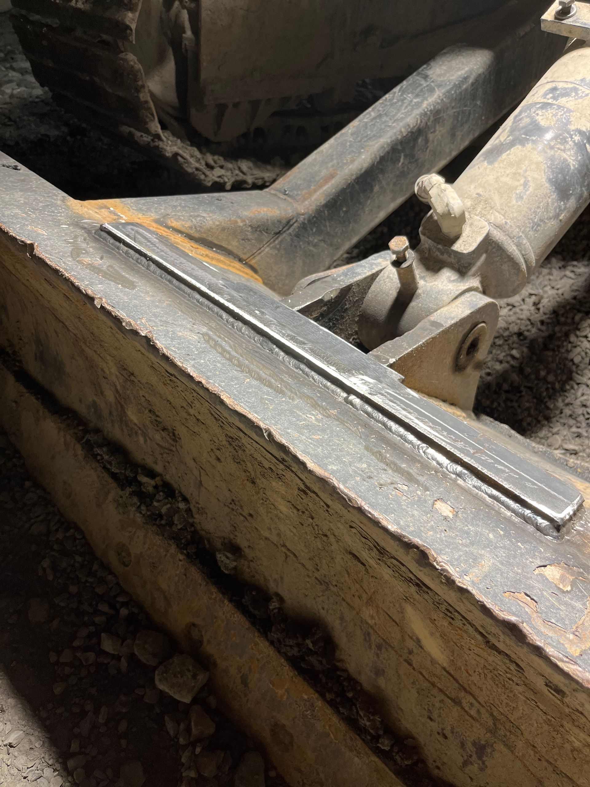 Plaque métallique soudée sur le bras d'une machine de construction, à l'intérieur.