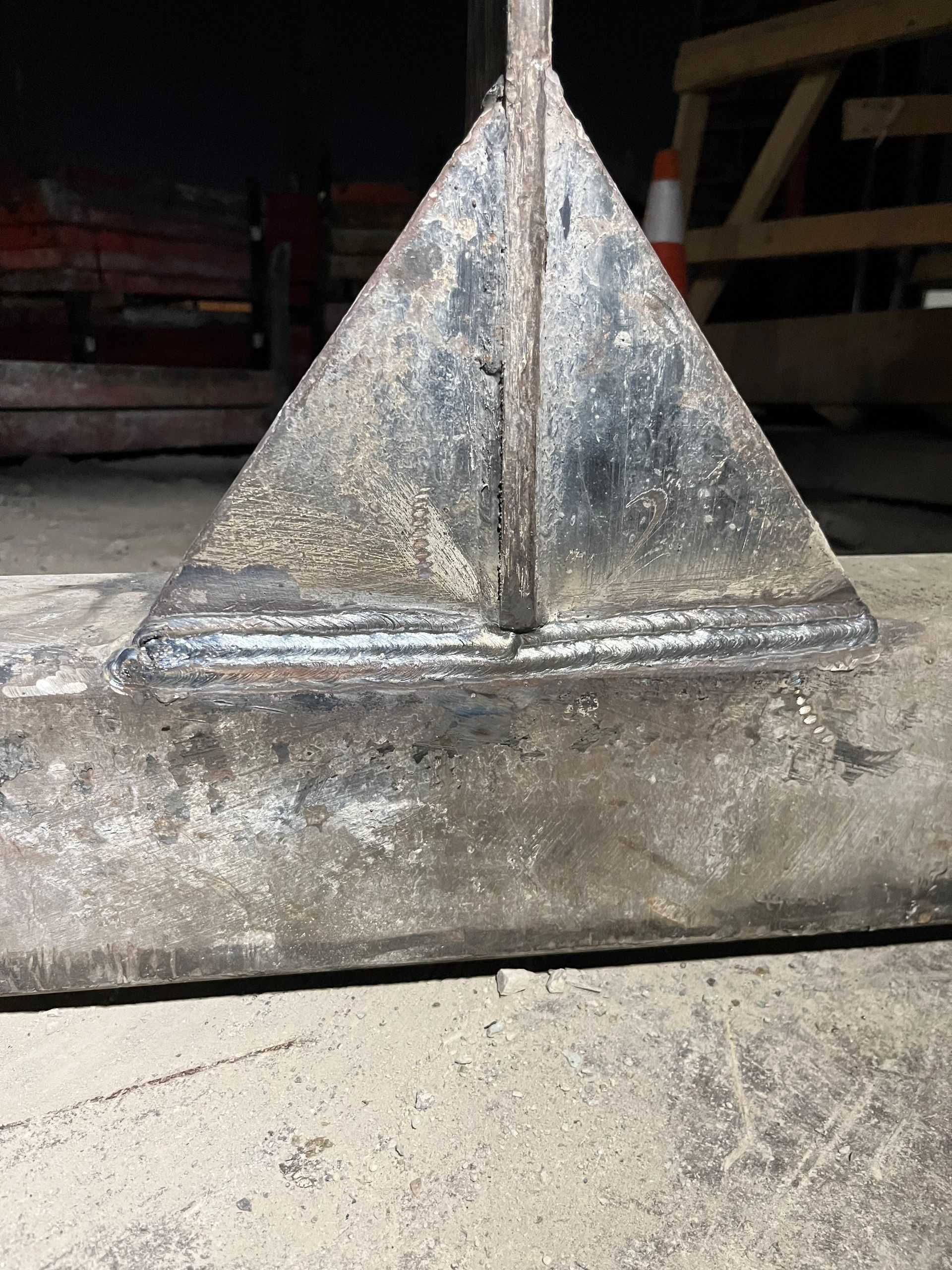 Structure métallique soudée : plaque triangulaire posée sur une poutre horizontale, probablement pour le support ou la construction.