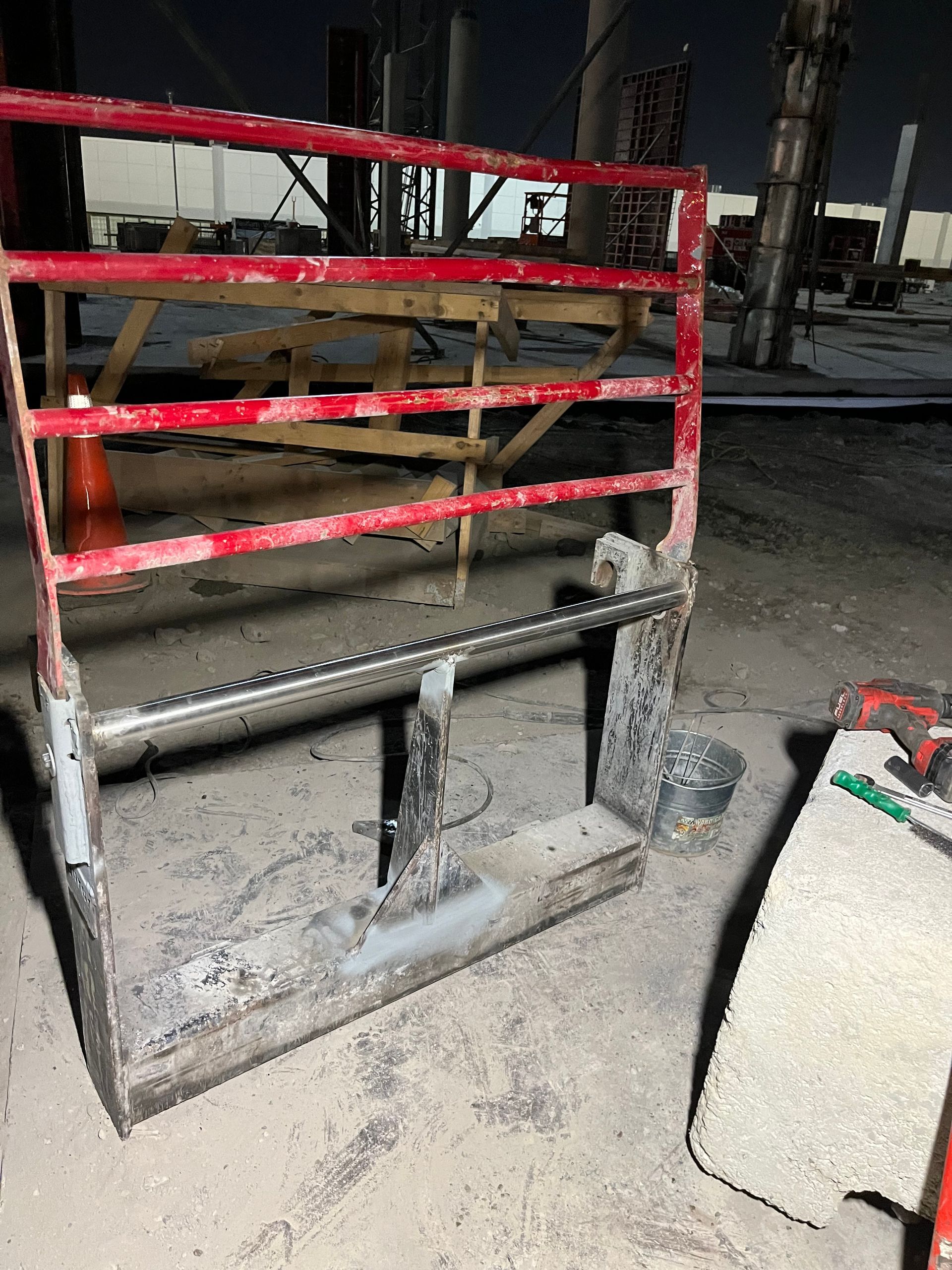 Portail métallique rouge sur béton, probablement pour un chantier de construction ou un site industriel.