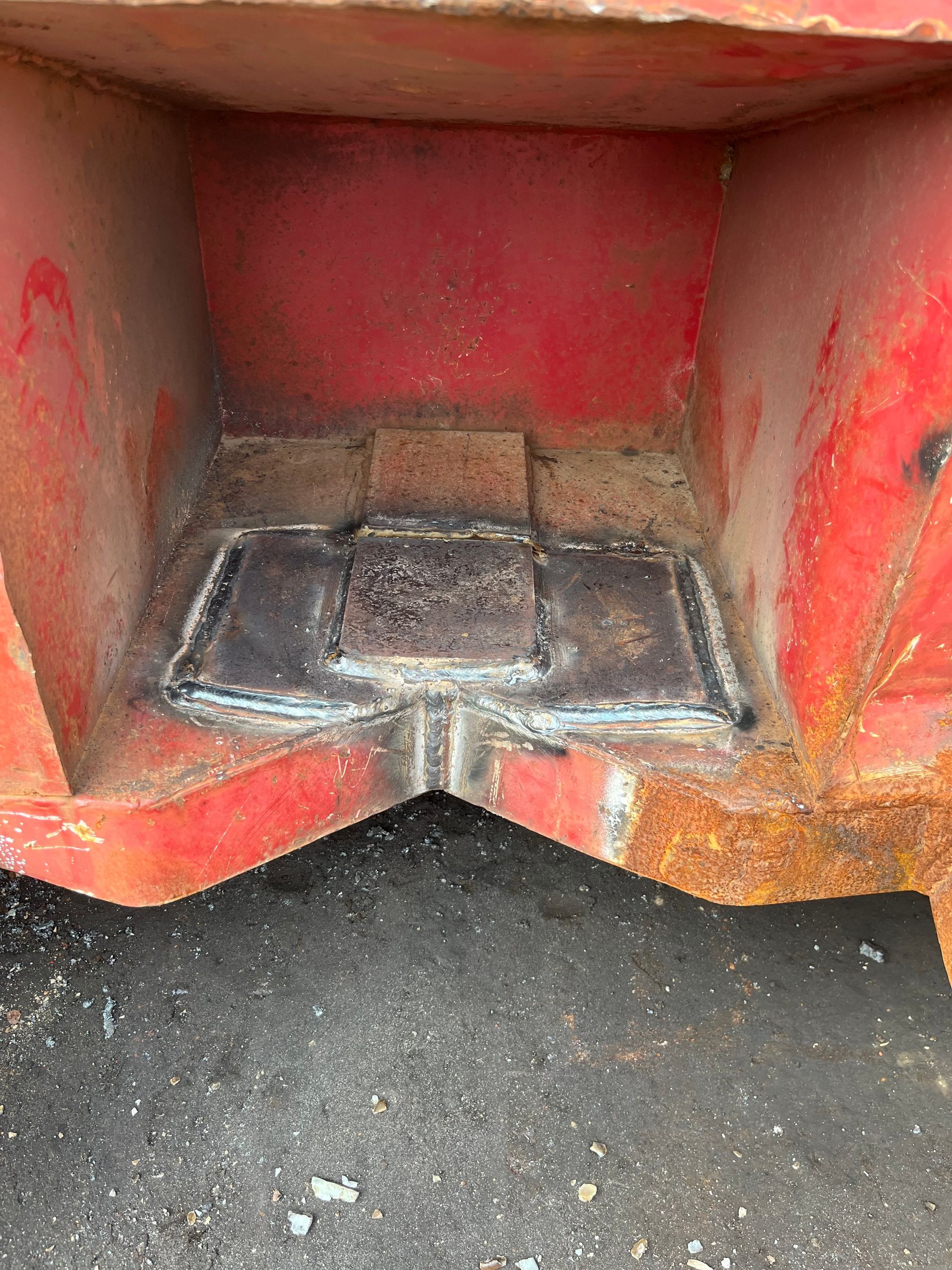 Pièces métalliques soudées à l'intérieur d'un conteneur rouge.