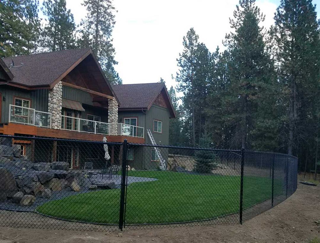 A large house with a fence in front of it surrounded by trees.