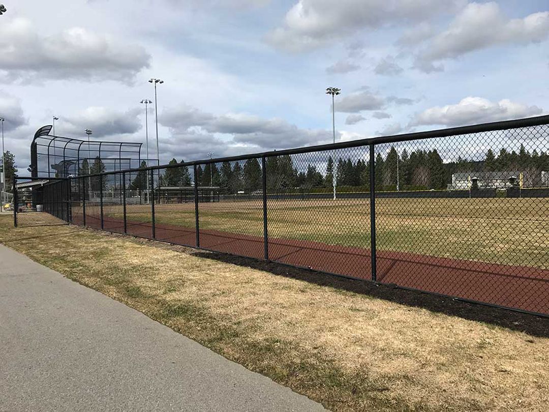 A chain link fence surrounds a baseball field.