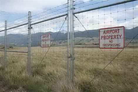 A barbed wire fence with a sign that says `` airport property no trespassing ''.