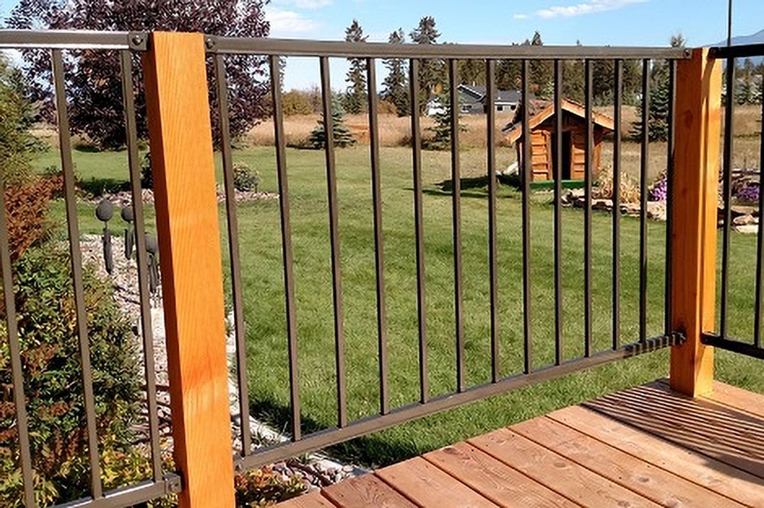 A wooden deck with a metal railing and a shed in the background