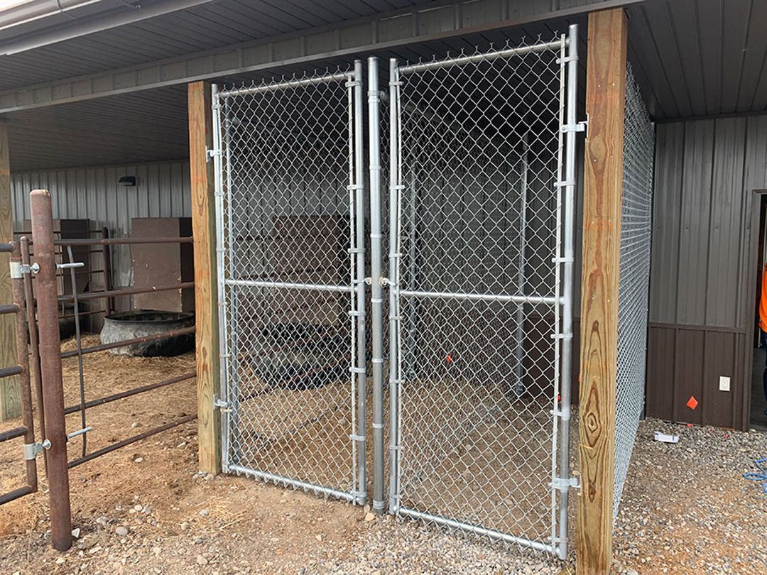 A chain link fence is surrounded by a wooden fence and a building.