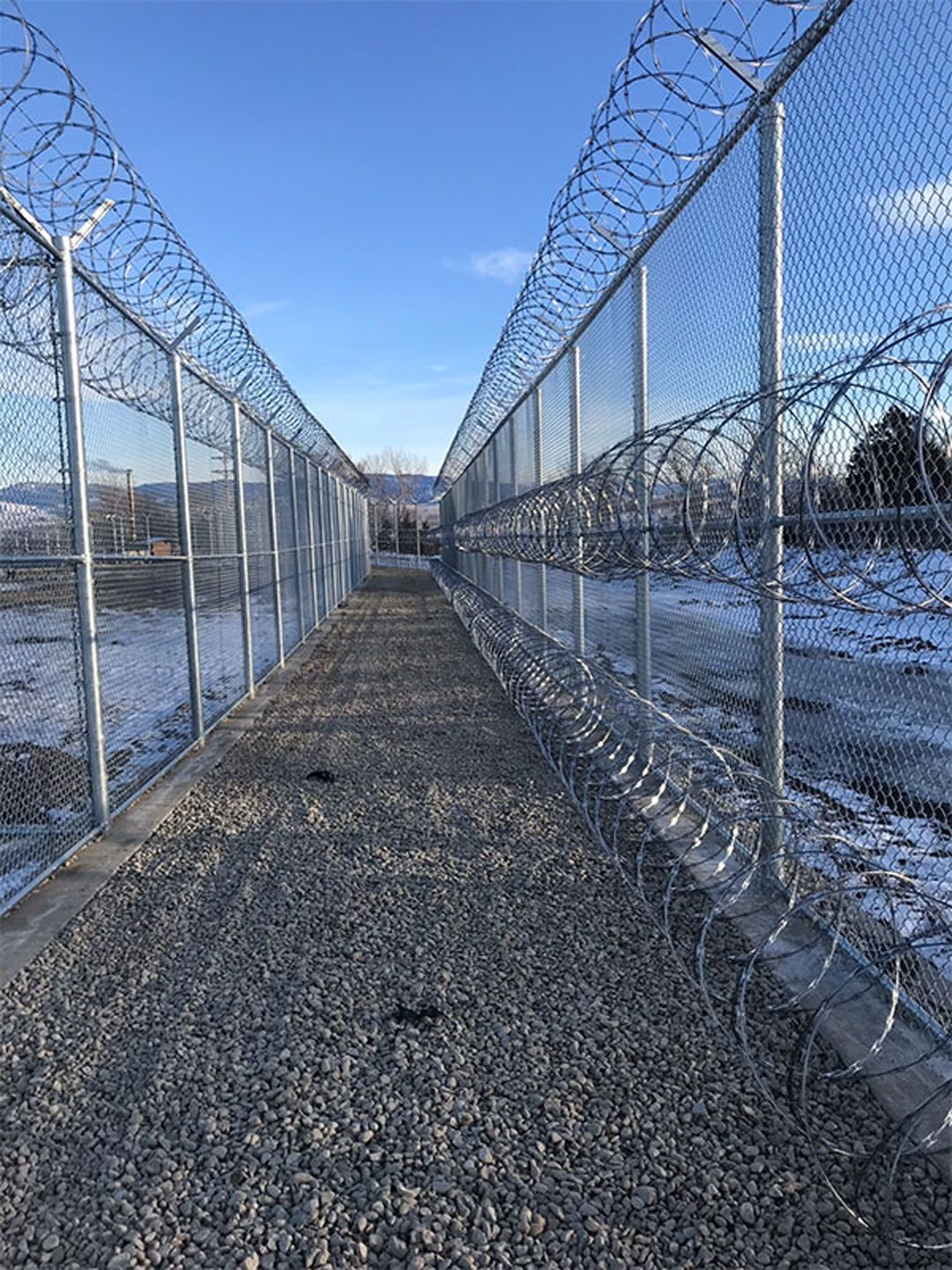 A barbed wire fence surrounds a gravel path.