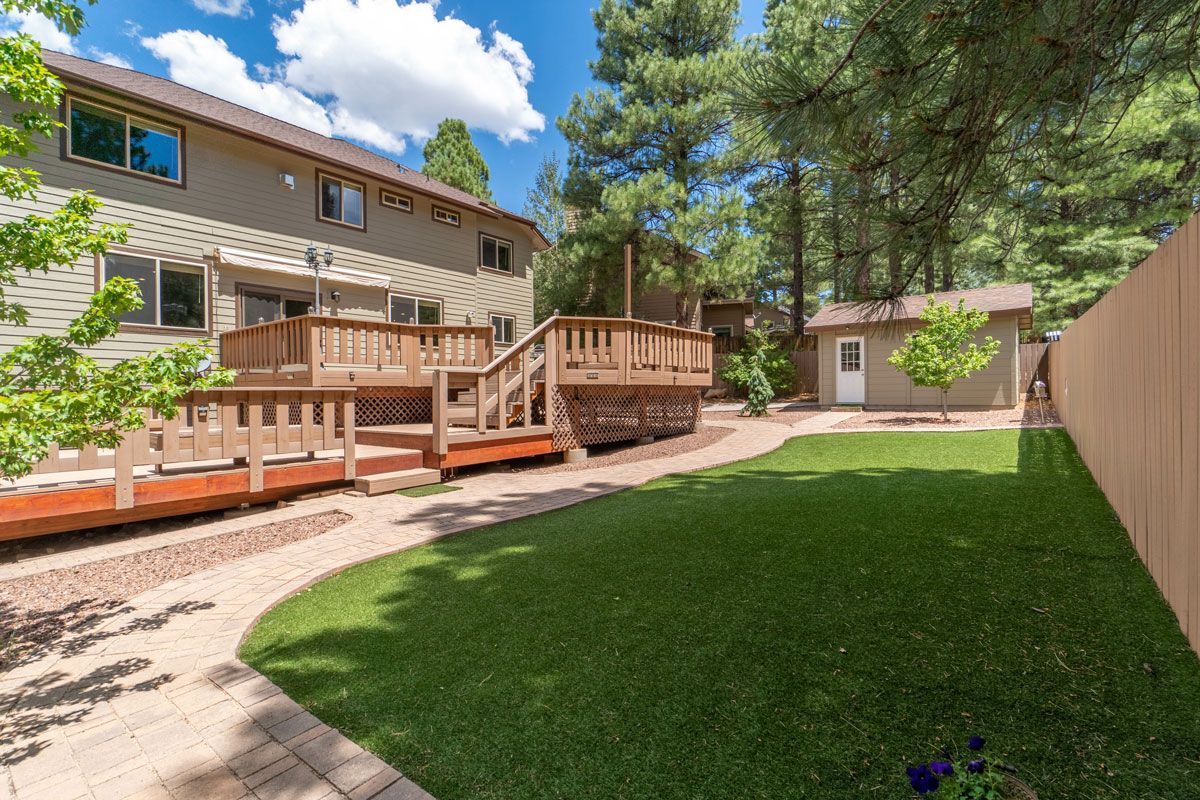The backyard of a house with a large deck and a fence.