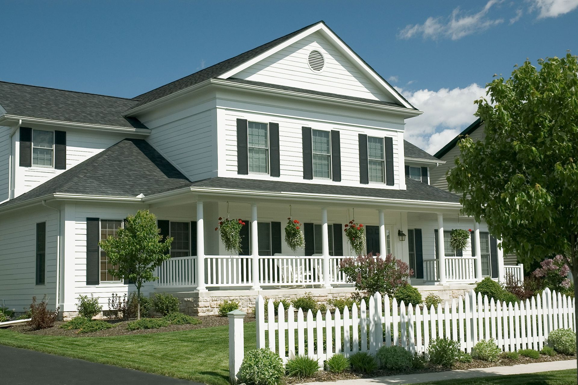 A large white house with a porch and a white picket fence