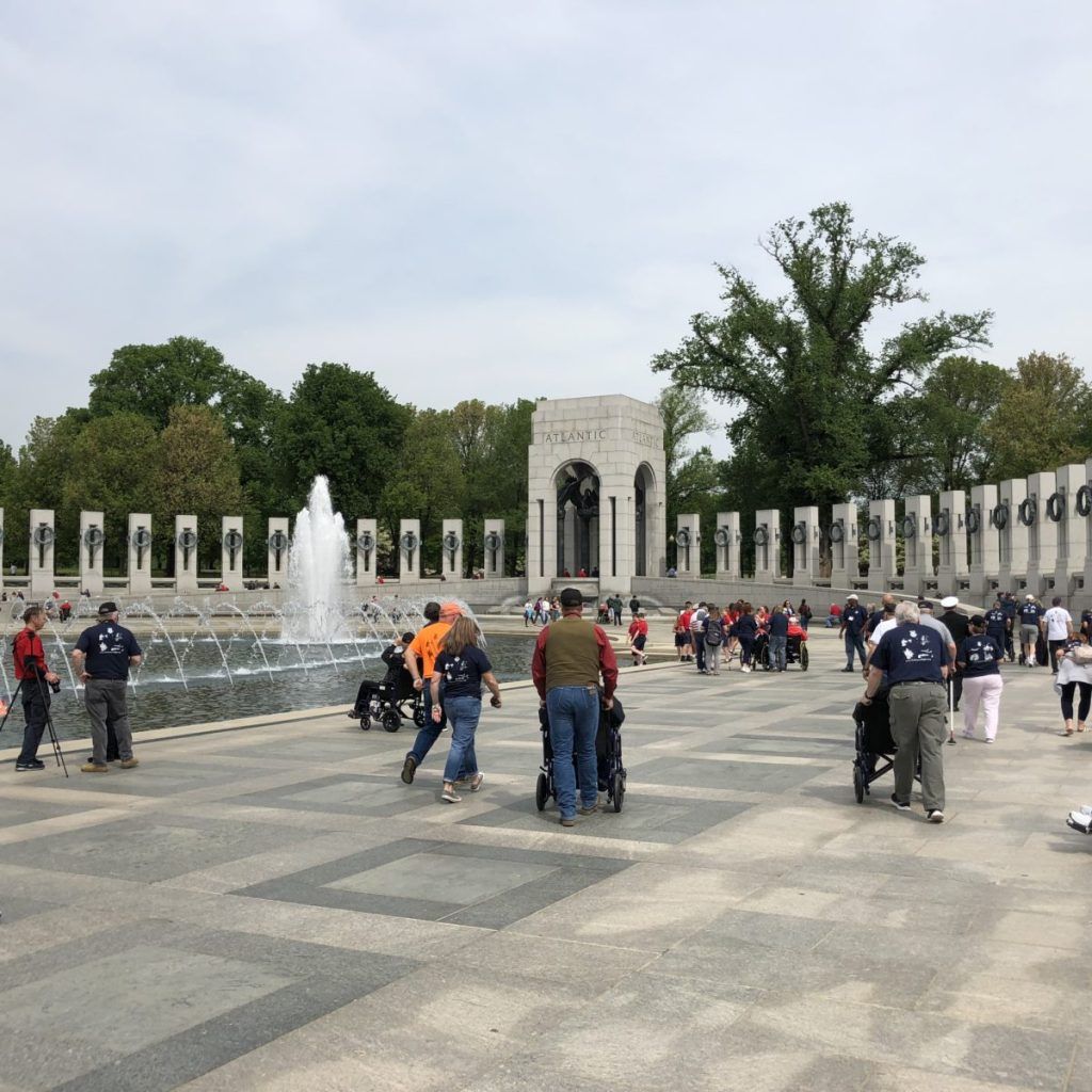 A group of people are walking in front of a fountain