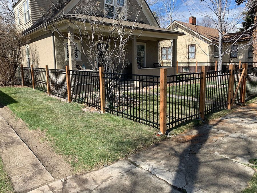 A house with a fence around it and a sidewalk in front of it.