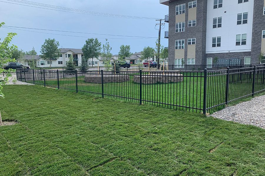 A large lawn with a fence in front of a building.