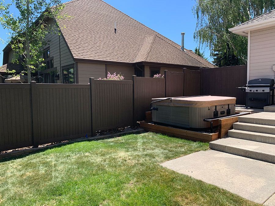 A hot tub is sitting in the backyard of a house next to a fence.