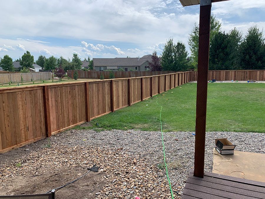 A wooden fence surrounds a lush green yard.