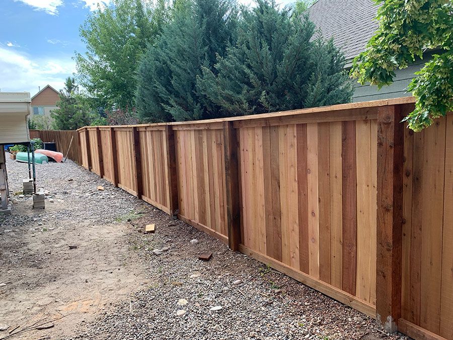 A wooden fence is being built in the backyard of a house.