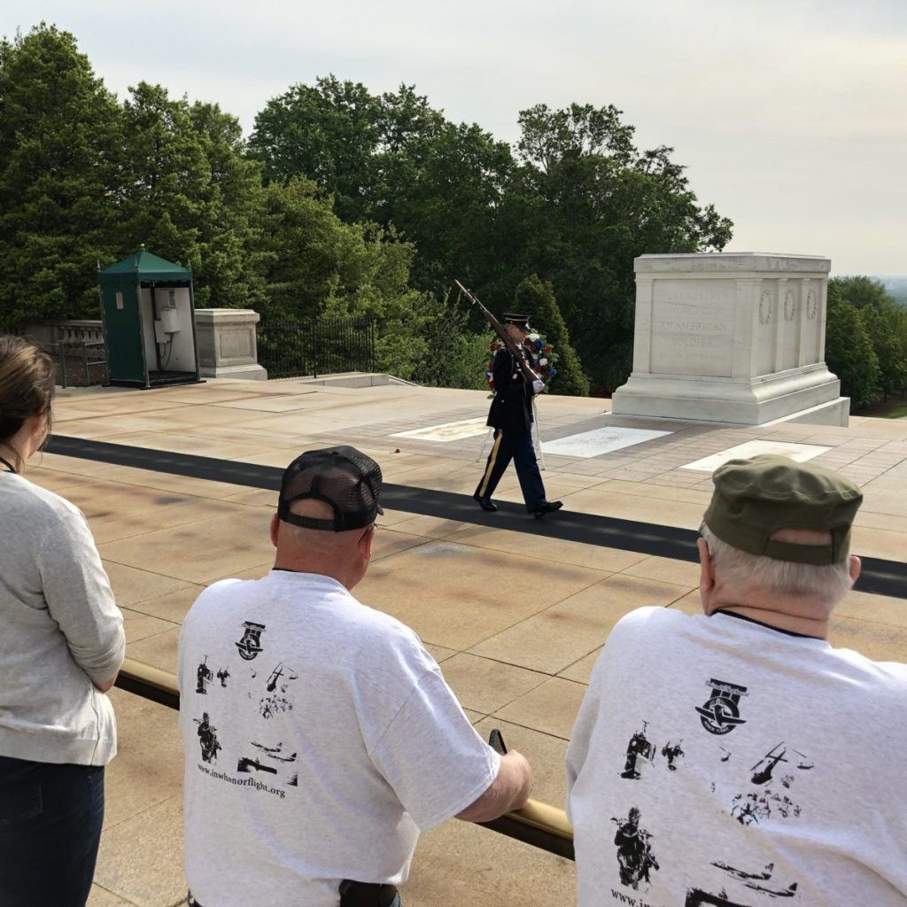 A man playing a trumpet in front of a monument