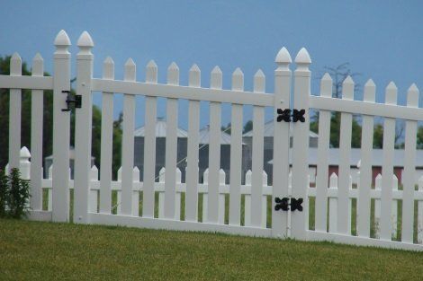 A white picket fence with a gate in the grass