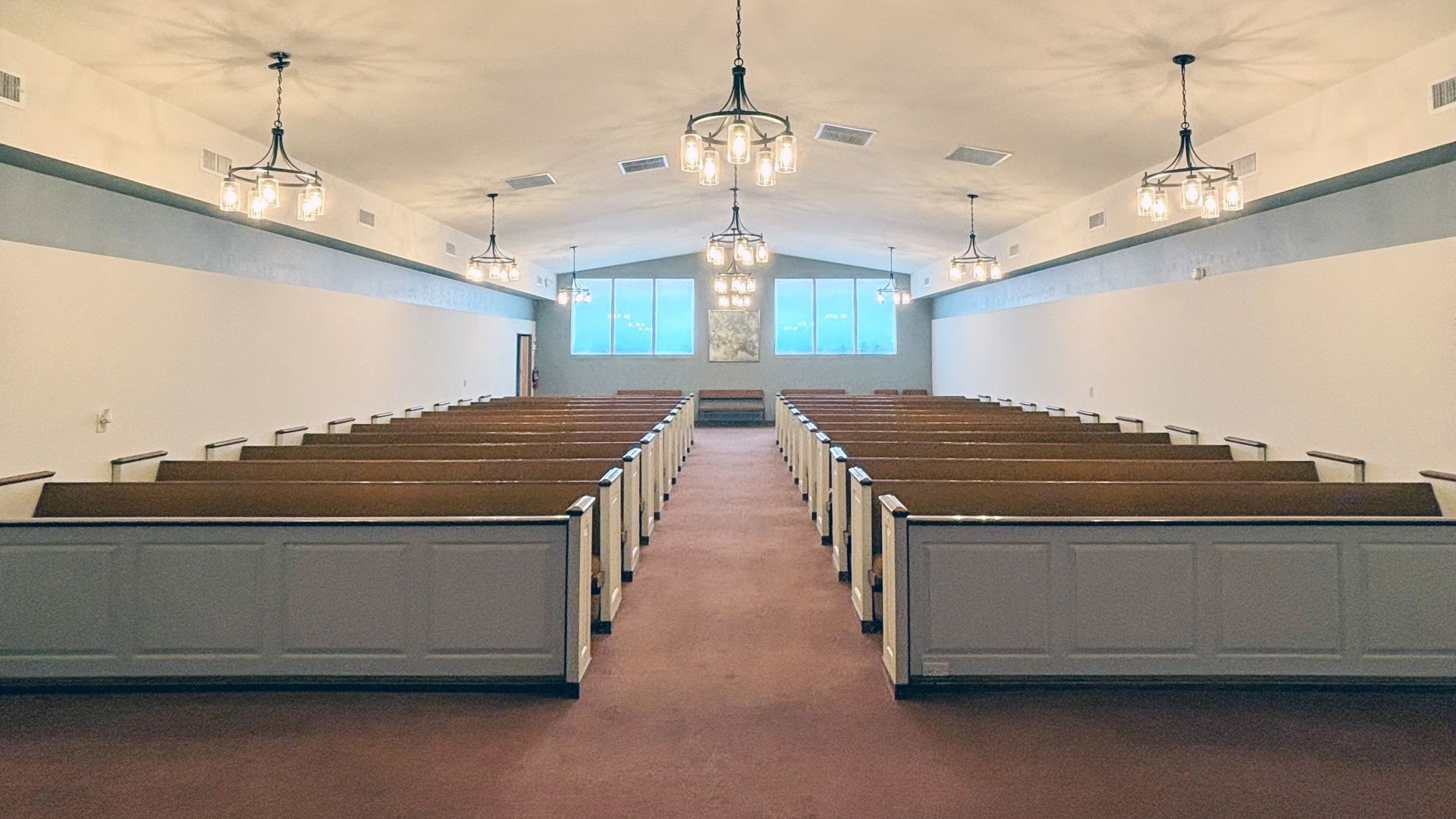 Large foyer with round wooden table, chandelier, and a vase of flowers.
