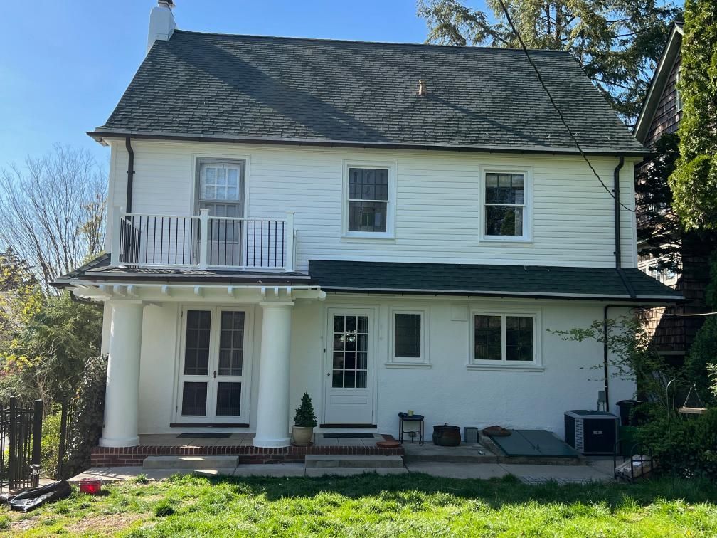 Gray asphalt shingle roof on a building, seen from above. A truck is parked in the background.