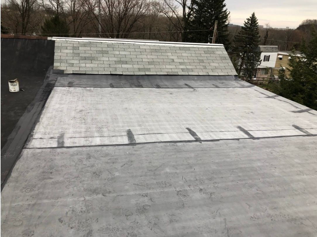 Flat gray roof with a brick chimney and a dark black border.