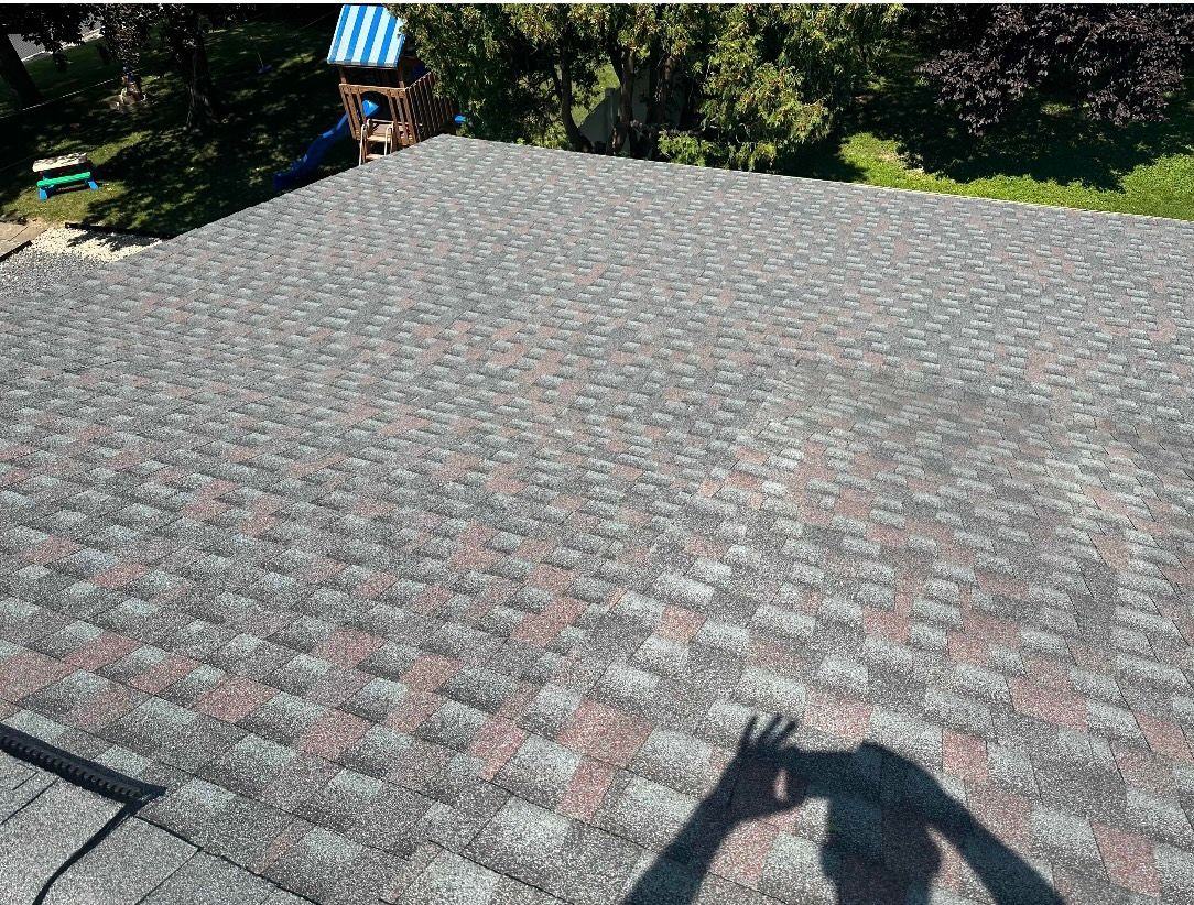 Small white house with dark roof, chimney, and open door. Brown dumpster and debris in front.