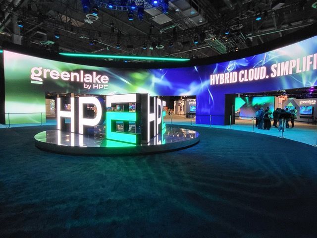 HP GreenLake booth at a tech event. Features large HP logo, and curved LED display with product info.