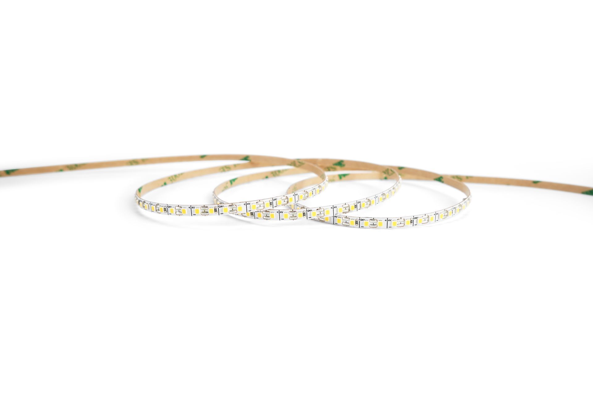 LED light strip coiled on a white surface, showing adhesive backing.