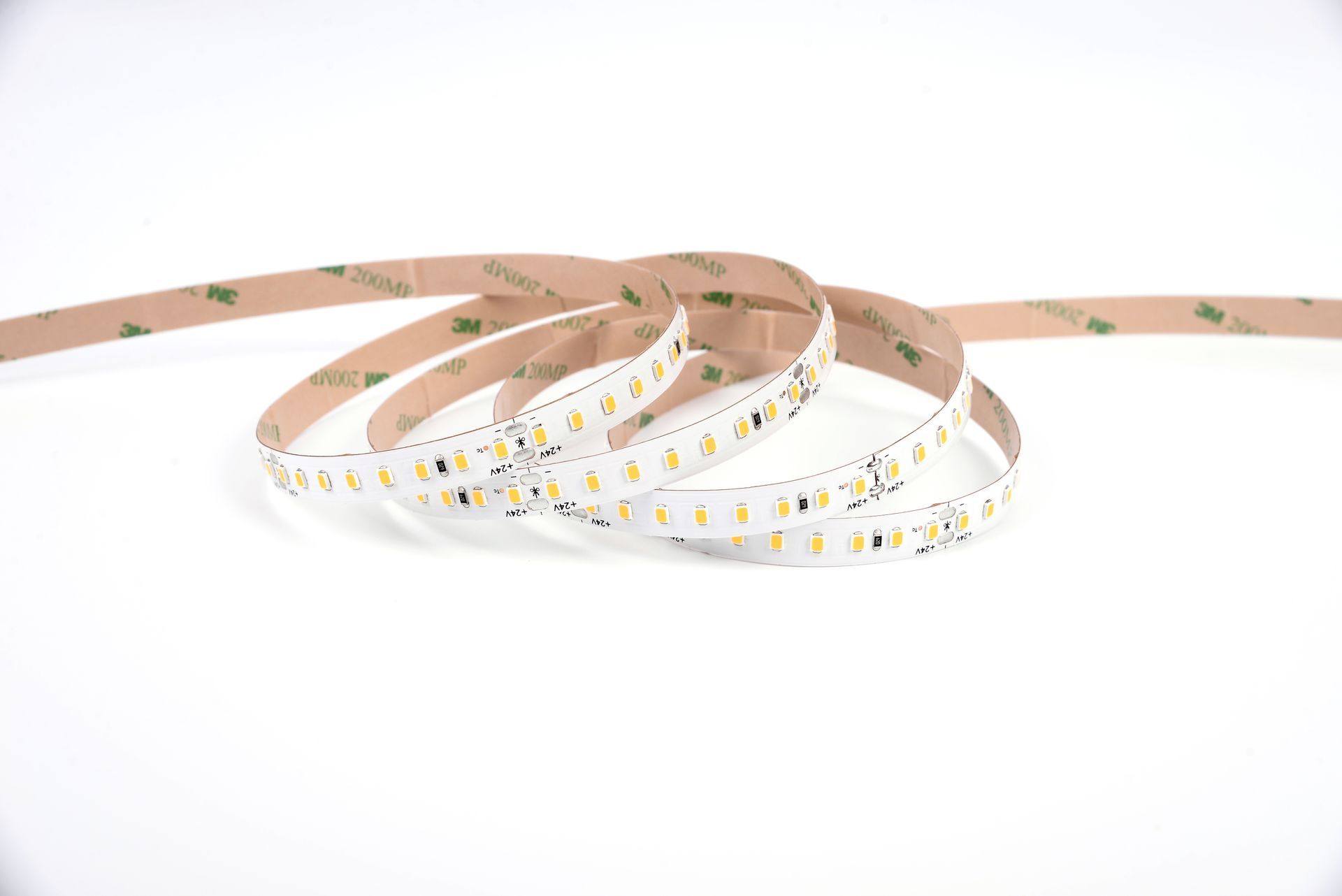 LED strip light coiled on white background, showing lights and adhesive backing.