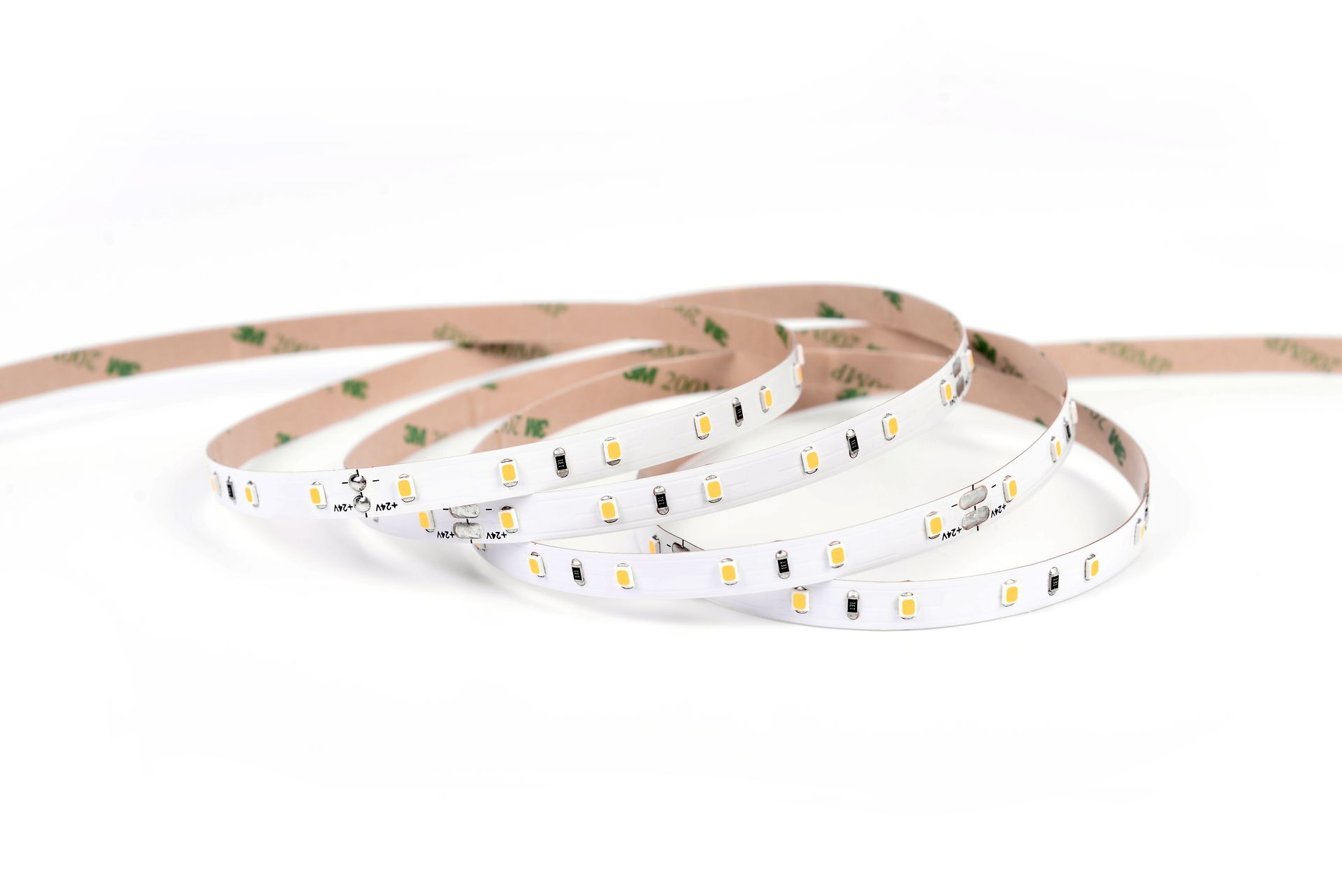 LED strip light coiled on a white surface, revealing the LEDs and adhesive backing.
