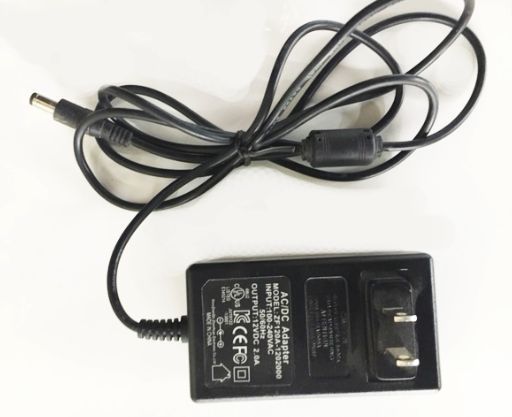 Black AC/DC adapter with a power cord and a DC barrel connector on a white surface.