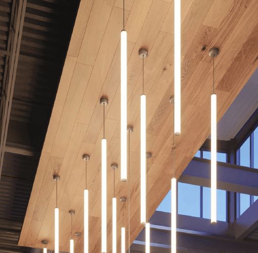 Light fixtures hang from a wooden ceiling in a building interior.