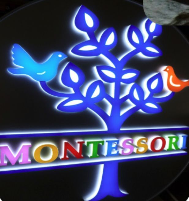 Sign for Montessori school: a blue tree with leaves and birds, and rainbow text