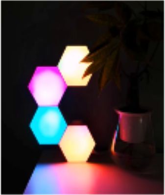 Hexagonal color-changing LED lights illuminate a dark room; some are pink, blue, and yellow.