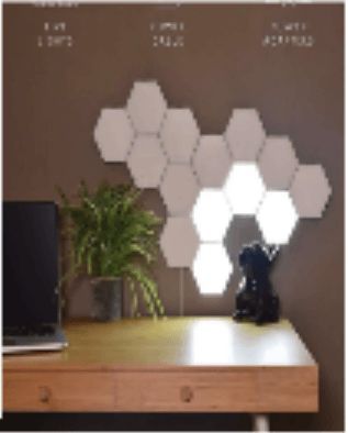 Hexagon-shaped LED lights on a wall above a wooden desk. A plant, a laptop, and a camera are visible on the desk.