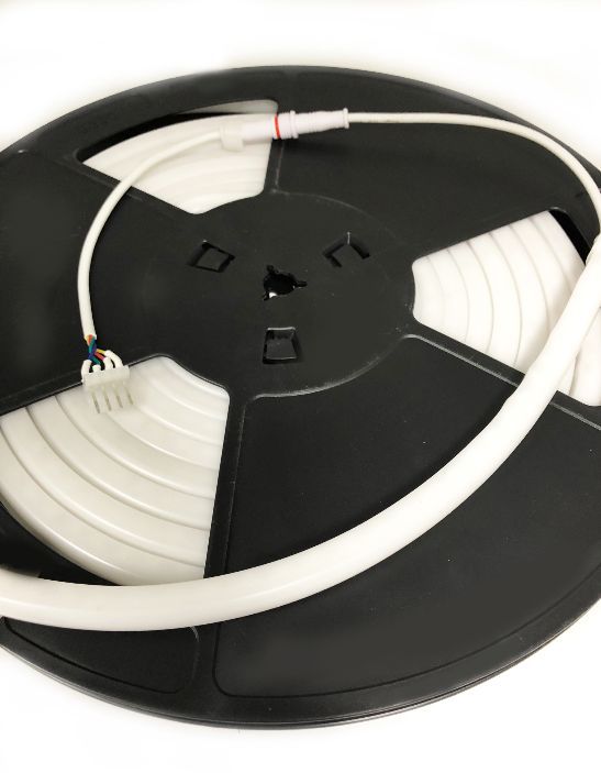 Spool of white LED strip lighting with attached power connector; on a black spool.