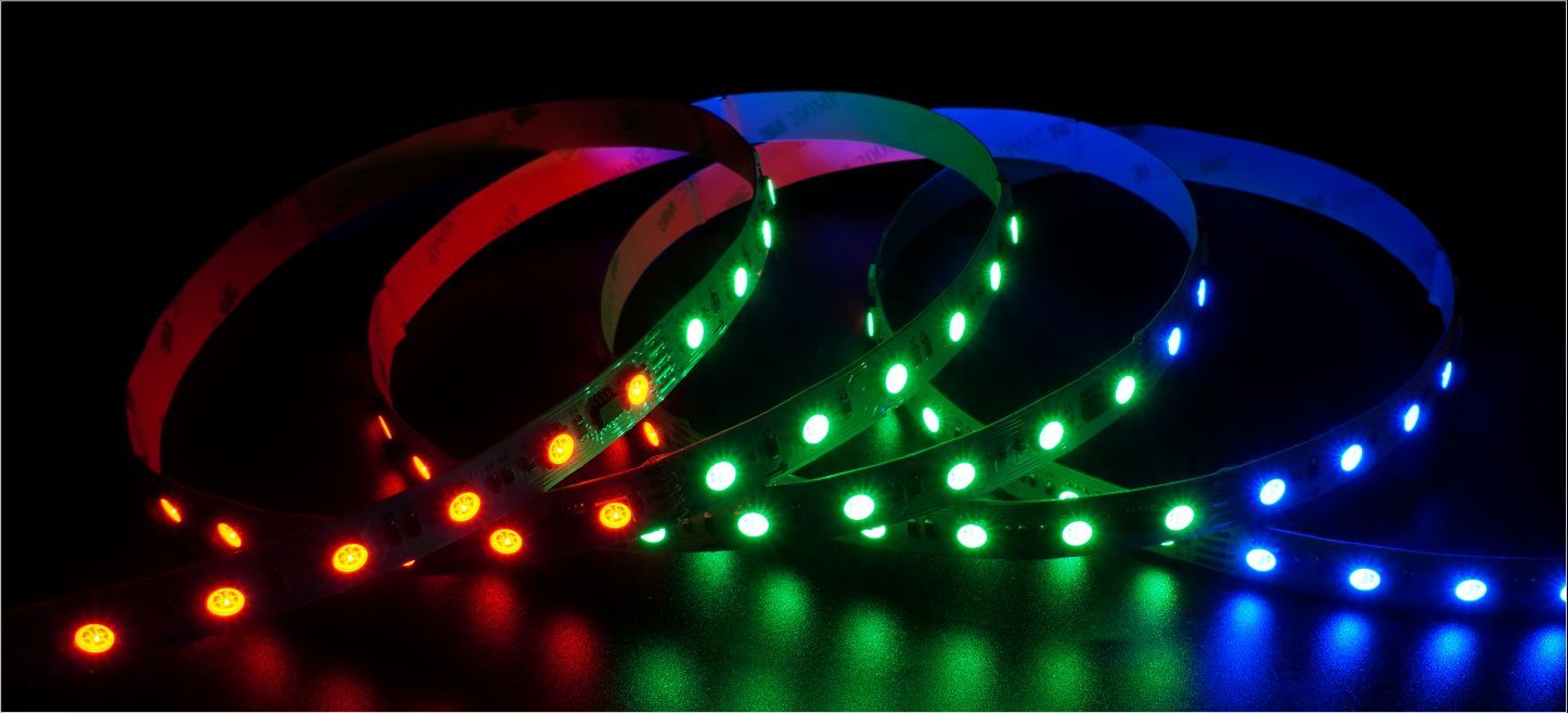LED light strips, coiled, emitting orange, red, green, and blue light against a black background.